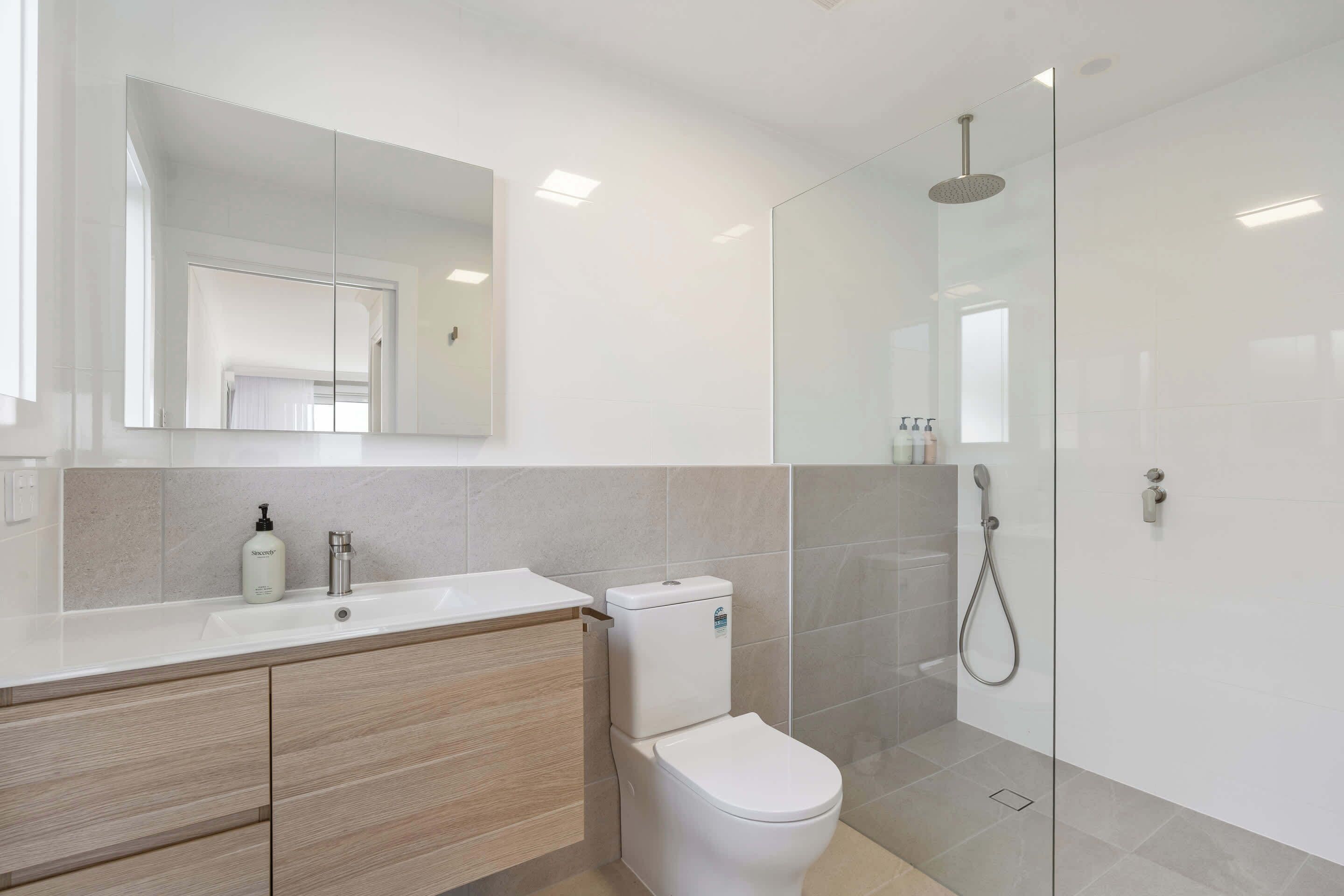 A modern bathroom with a toilet, sink, and shower.