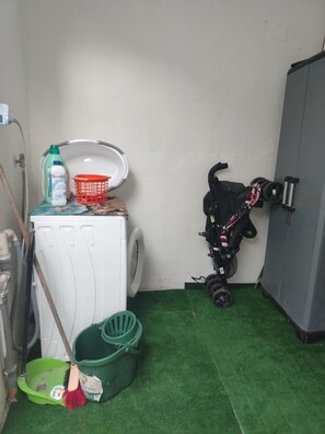 A laundry area with a washing machine, a stroller, and a mop. - 'Lucky House' Apartment with Wi-Fi and Air Conditioning (Muravera)
