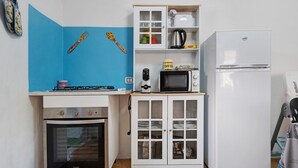 Eine kleine Küche mit Gaskochfeld, Mikrowelle und einem weißen Kühlschrank.