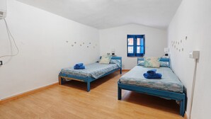 Ein Zimmer mit zwei Einzelbetten, einem Fenster und einer wandmontierten Lampe.