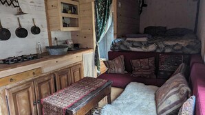 A rustic cabin interior with a wooden stove, a bench, a sofa, and a bunk bed. - Charming gypsy caravan in green Provence, at La Mauvaise Herbe, Barjols (Barjols)