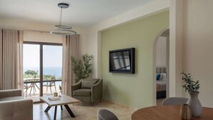 Uma sala de estar moderna com um sofá, uma mesa de centro e uma mesa de jantar. Há uma televisão fixada na parede e uma planta no chão.