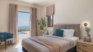 Quarto com cama, mesa de cabeceira e vista para o mar.