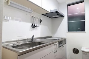 A modern kitchen with stainless steel appliances, a double sink, and hanging utensils. - nestay inn tokyo senju (Tokyo)