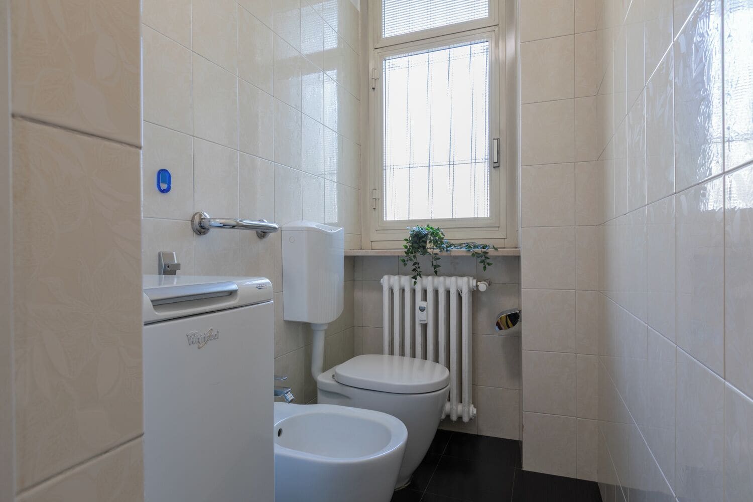 A compact bathroom with a toilet, bidet, and a radiator.