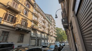 Une rue étroite, bordée de voitures garées et de bâtiments à plusieurs étages dotés de balcons.