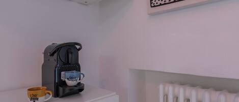 Una cafetera sobre un estante blanco, con dos tazas: una con la frase 'Good Morning' y otra con 'Love Coffee'.