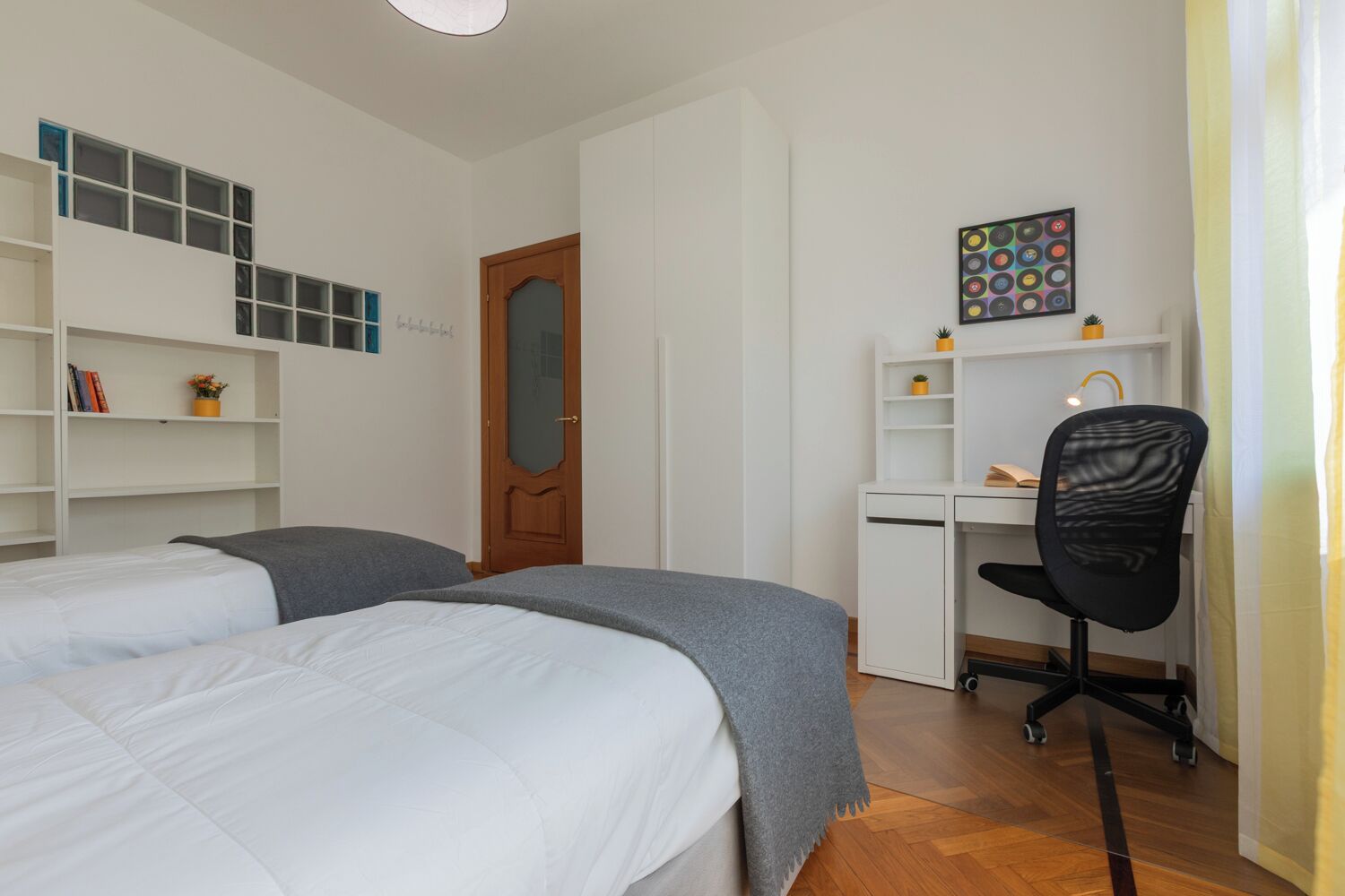 Un dormitorio con dos camas, un escritorio, una silla y una estantería.
