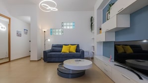 Un salon moderne avec un canapé gris, une table basse ronde et un téléviseur à écran plat.