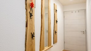 Un couloir avec trois miroirs en bois fixés aux murs, une porte blanche et une décoration florale rouge.