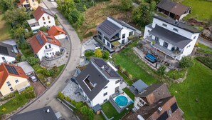Vue aérienne d’un quartier résidentiel avec des maisons modernes, une piscine et des panneaux solaires.