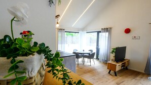 Una sala de estar moderna con una mesa de comedor de madera, un mueble para televisión y un balcón con vistas.