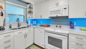A modern kitchen with white cabinets, a microwave, a dishwasher, and a stove. - Treasure Sands #502 (Treasure Island)