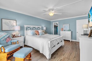 A bedroom with a bed, a chair, a nightstand, a dresser, and a ceiling fan.