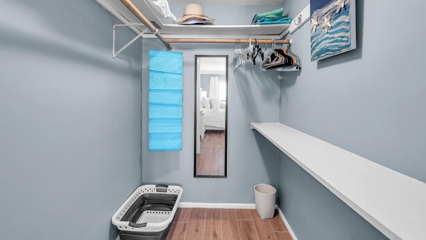 A compact room with a built-in closet, a hanging rack, a small laundry basket, and a mirror. - Treasure Sands #502 (Treasure Island)