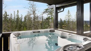 Un jacuzzi con plataforma de madera y vista a árboles.