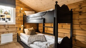 Habitación con literas, paredes de madera, una ventana y un calentador.