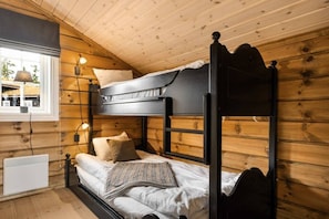 Habitación con literas, paredes de madera, una ventana y un calentador.