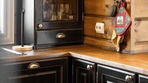 Una cocina con pared de madera, un mueble negro con puerta de vidrio y una bolsa roja colgada en la pared.