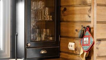 A kitchen with a wooden wall, a black cabinet with a glass door, and a red bag hanging on the wall.