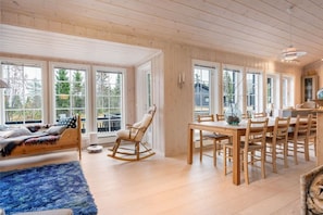 A spacious room with a large dining table, a rocking chair, and a cozy seating area with a blue rug. - FA303 Premium ski-in/out cabin in Trysil hottub & sauna (Trysil)