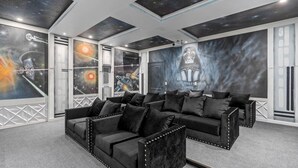 Una habitación con sofá modular, un ventanal grande y un mural con motivos espaciales.