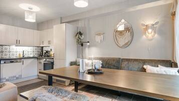 A modern kitchen with white cabinets, a dining table, and a seating area with a sofa and cushions.