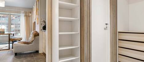 A modern interior with a built-in wardrobe, a seating area, and a view through a window.