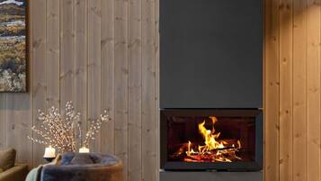 A modern living room with a fireplace, wooden panel walls, and a cozy seating area.