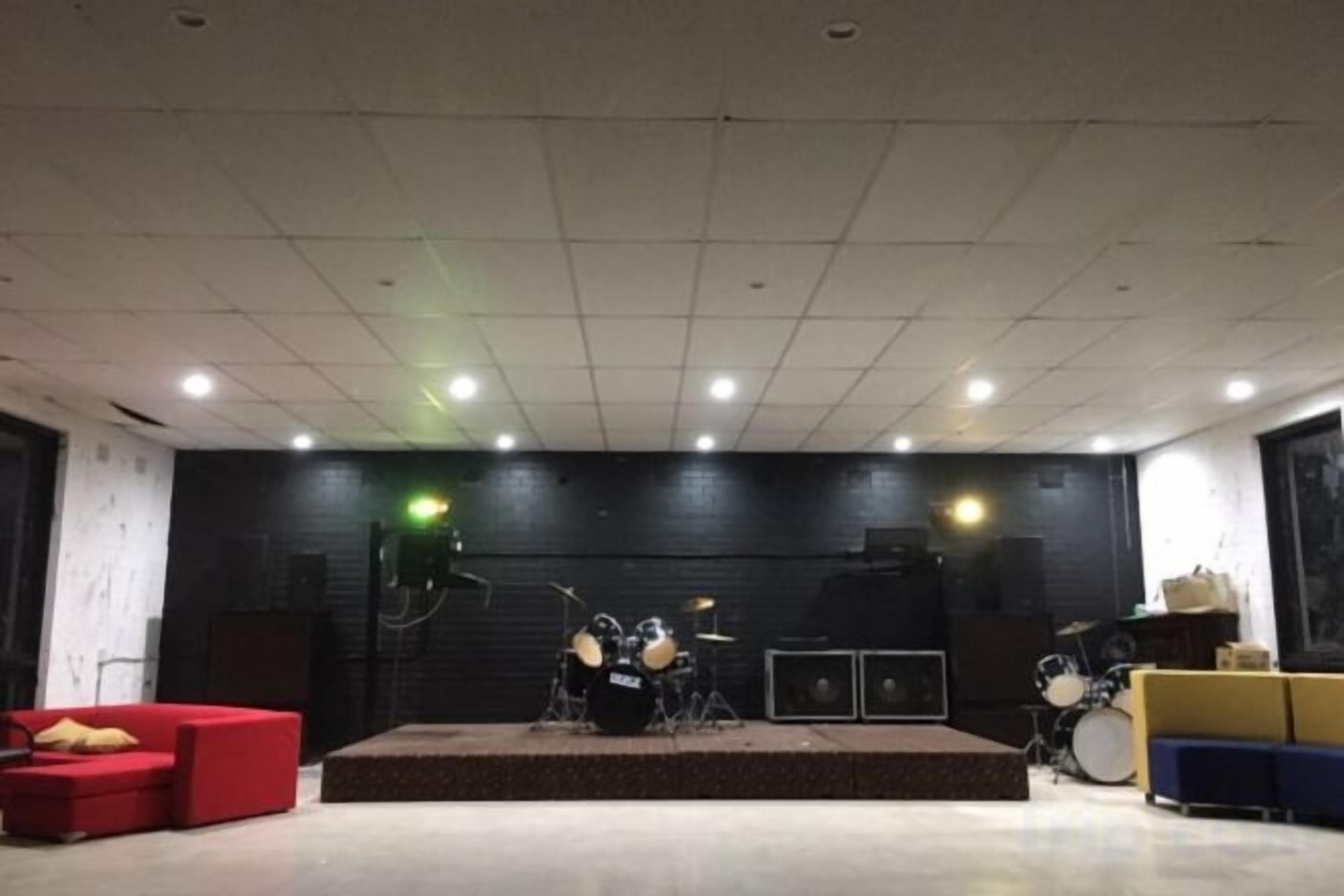 A stage with musical instruments, a red sofa, and a blue bench.