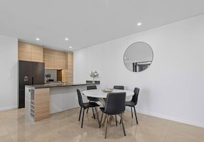 A modern kitchen with a built-in refrigerator, wooden cabinets, and a round mirror on the wall.
