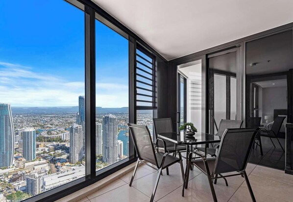 A modern room with a large window offering a city view, a dining table with chairs, and a small plant on the table.