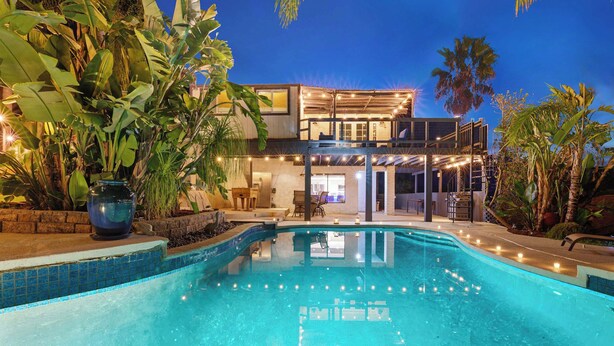 A modern two-story house with a swimming pool, surrounded by tropical plants and illuminated by string lights. - Elegant Hillside Estate | Heated Pool+Sunset Views (El Cajon)