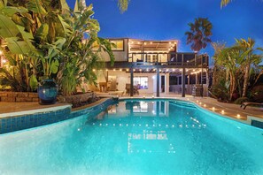 A modern two-story house with a swimming pool, surrounded by tropical plants and illuminated by string lights. - Elegant Hillside Estate | Heated Pool+Sunset Views (El Cajon)