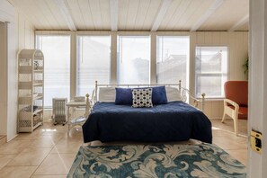 A bedroom with a bed, a white radiator, a white shelving unit, and a red chair.