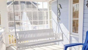 A porch with a white swing and a blue chair, a white fence, and a house with a white exterior. - 2 Streets to the Beach! Game Room BBQ & Firepit (Seaside)