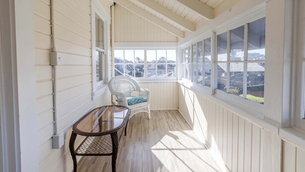 A covered porch with a table and a chair, large windows, and a view of the neighborhood. - 2 Streets to the Beach! Game Room BBQ & Firepit (Seaside)