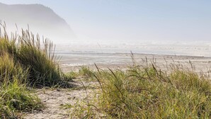 A beach with sand dunes and grass in the foreground, leading to a calm sea under a clear sky. - 2 Streets to the Beach! Game Room BBQ & Firepit (Seaside)