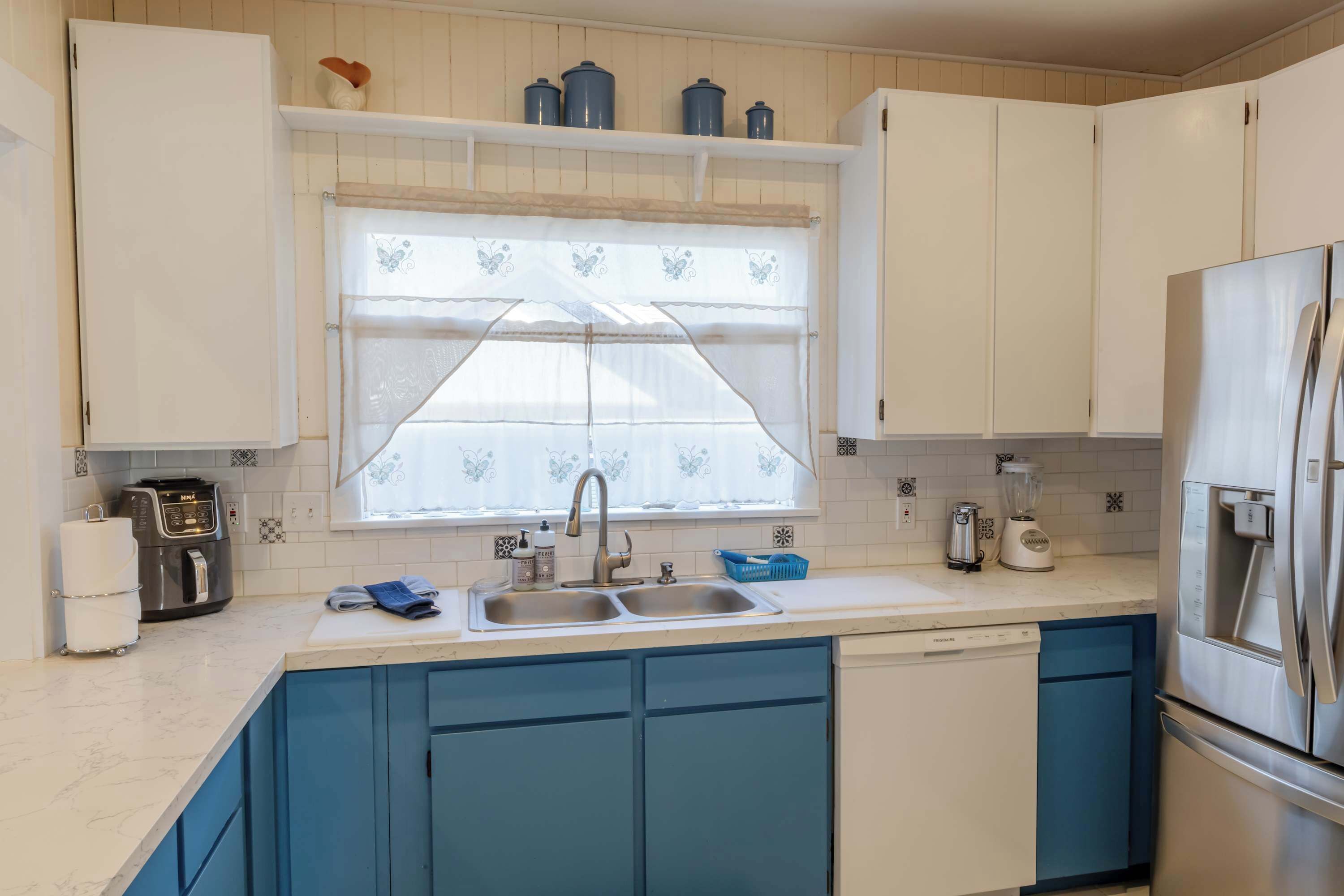 Una cocina con un lavamanos doble, lavavajillas integrado y un refrigerador.
