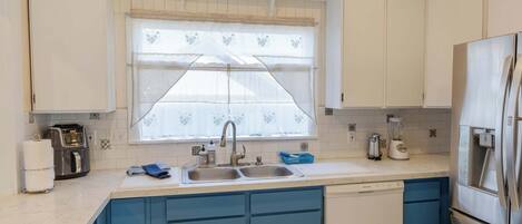 Una cocina con un lavamanos doble, lavavajillas integrado y un refrigerador.