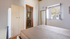 Une chambre à coucher avec un lit, une armoire, une porte de salle de bain et une fenêtre.