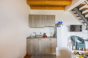 Una cucina compatta con mobili in legno, forno a microonde integrato e zona pranzo con sedia e tavolo.