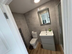 A compact bathroom with a toilet, sink, and mirror. - Riverside Retreat in Staines-upon-thames (Staines)