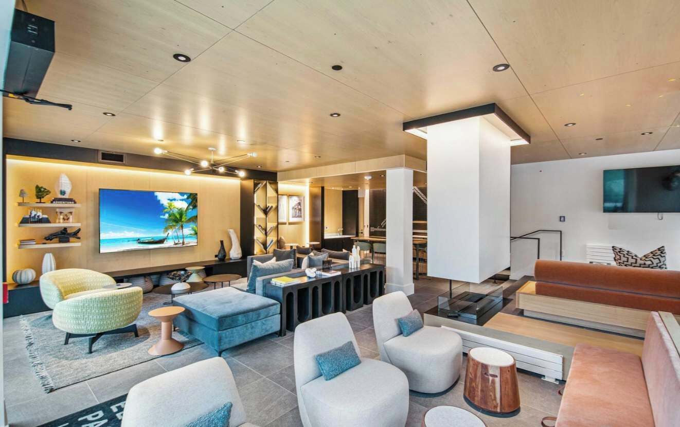 A modern living room with a large flat-screen TV, comfortable seating, and a staircase leading to an upper level.
