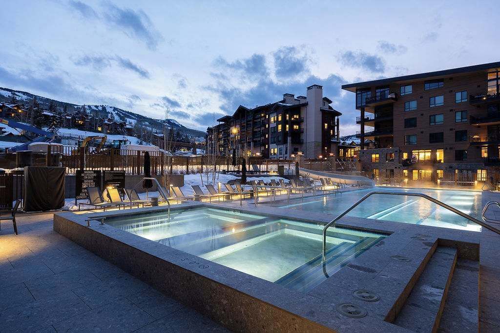 A hotel pool area with lounge chairs and a pool, surrounded by buildings with multiple floors and balconies.