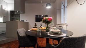 A modern dining area with a round table, two chairs, a vase with flowers, and a television on the wall. - Italianway Comfort - Vincenzo Monti 29 D (Milan)