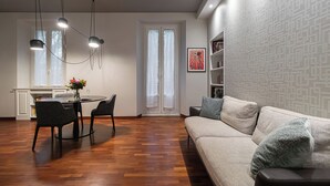 Un salon moderne avec un canapé, une table à manger et des chaises. Il y a également un coin cuisine avec une fenêtre et une porte.