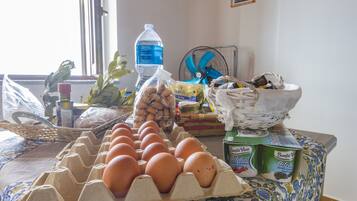 A kitchen counter with eggs, a water bottle, a fan, and a basket of bread.