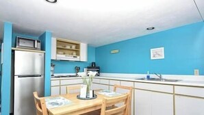 Une cuisine de taille réduite équipée d’un réfrigérateur, d’un évier et d’une table à manger avec des chaises.