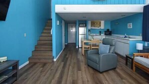 Un espace de vie compact comprenant une cuisine, un coin repas et un escalier menant à un niveau supérieur.